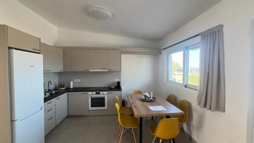 a kitchen with a wooden table and yellow chairs at Radiki in Gennadi