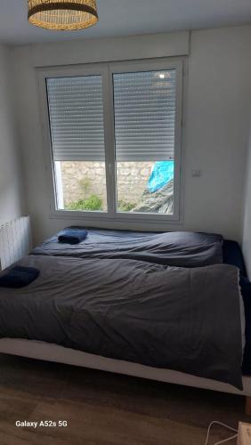 a bed in a room with two windows at SER3 votre F2 avec wifi et parking à Saint-Etienne-Du-Rouvray in Saint-Étienne-du-Rouvray
