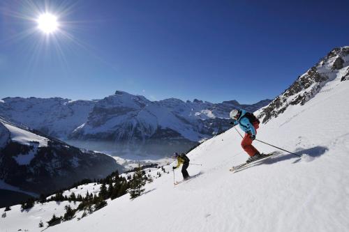 two people are skiing down a snow covered mountain at Berglodge Ristis in Engelberg