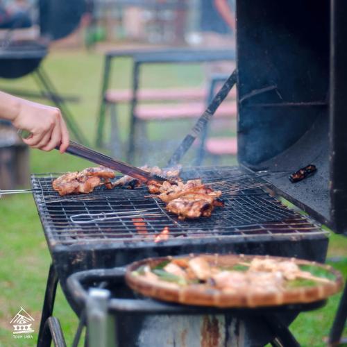 a person is cooking meat on a grill at Chez Vous House - Toom Sara in Mang Son