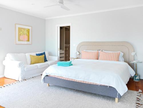 a bedroom with a large bed and a white couch at Beilby Inlet Views in Inverloch