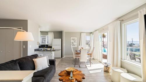 a living room with a black couch and a kitchen at 4 Cayucos Bungalows Steps to Beach Sleeps 16 Pet Friendly in Cayucos