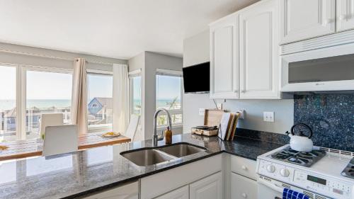 a kitchen with white cabinets and a sink and a stove at 4 Cayucos Bungalows Steps to Beach Sleeps 16 Pet Friendly in Cayucos