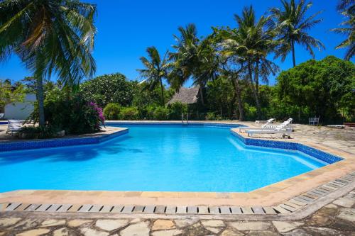 a swimming pool with palm trees in the background at ZIA Homes DIANI in Mombasa