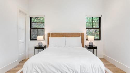 1 Schlafzimmer mit einem weißen Bett und 2 Fenstern in der Unterkunft Luxury Retreat 5mins to the Lake Game Room Fire Pit Howlite by AvantStay in Lake Arrowhead