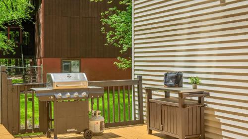 a barbecue grill and a table next to a fence at Stylish Mountain Retreat w Hot Tub Firepit Penn Estate Getaway by AvantStay in East Stroudsburg