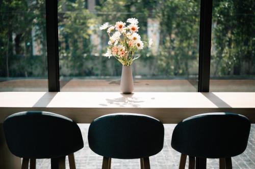 a vase of flowers sitting on a table with four chairs at Laike Hotel in Bangkok