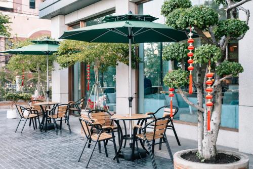 an outdoor cafe with tables and chairs and an umbrella at Laike Hotel in Bangkok