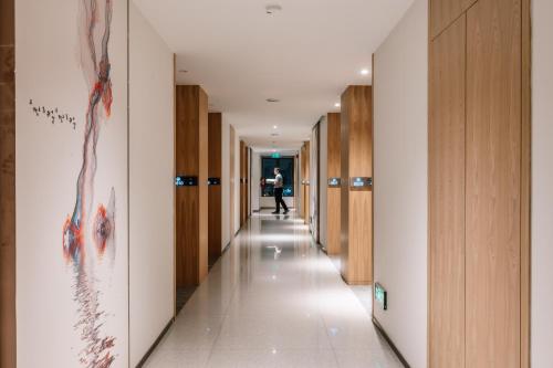 a hallway with wooden doors and a person walking down it at Laike Hotel in Bangkok