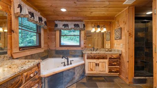 ein Badezimmer mit einer Badewanne und einem Waschbecken in der Unterkunft Big Bear Lodge by AvantStay Smoky Mountain Views Hot Tub Theater Game Room in Sevierville