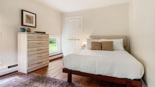 a bedroom with a white bed and a dresser at Pondfront Gem Minutes from Hudson’s Best Shops Cafes The Stillwater House in Hudson