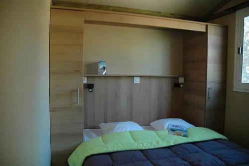 ein Bett in einem Zimmer mit einer Holzwand in der Unterkunft Camping les Pialades - Chalet Eden in La Mouline