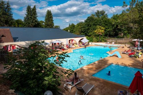 eine Draufsicht auf einen großen Swimmingpool mit Menschen darin in der Unterkunft Camping les Pialades - Chalet Eden in La Mouline