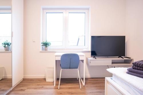 a room with a desk with a tv and a blue chair at Michelhuus 2 St Michaelisdonn in Westdorf