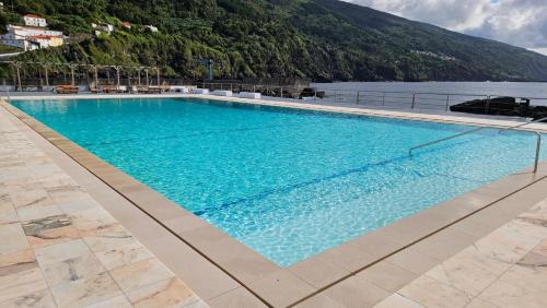 a large swimming pool next to a body of water at Casa Branca in Ribeiras