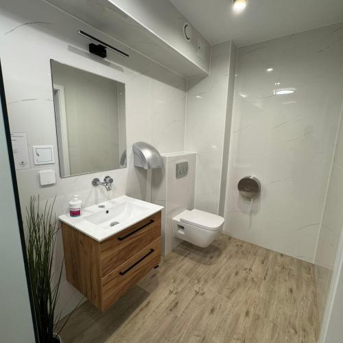 a white bathroom with a sink and a toilet at Hotel Vestina in Wisła
