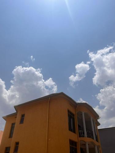 a yellow building with clouds in the sky at SAMNDAMZ Villa Apartment in Kigali