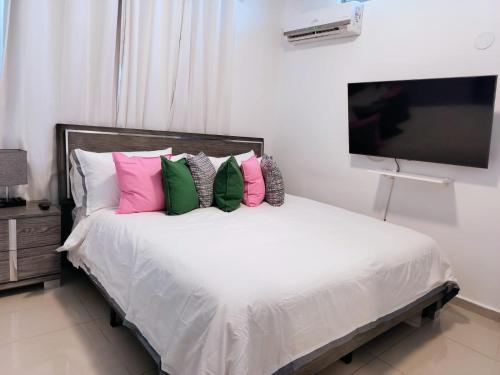 a bedroom with a bed with pink and green pillows at Aquaville Dorado Moderna Villa 4 in Dorado