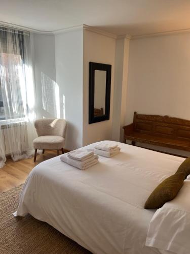 a bedroom with a large white bed and a chair at Casa Montaña de Riaño y Picos de Europa I in Riaño