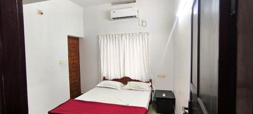 a small bedroom with a bed with a red blanket at Sea Breeze Cherai Homestay in Pallipuram