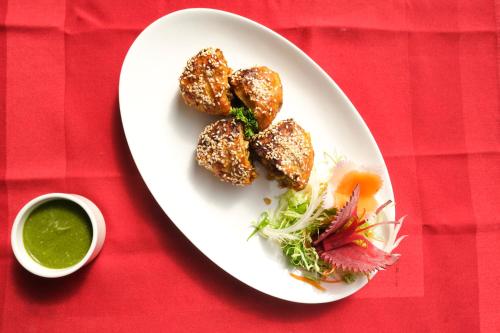 a white plate with food on a red table at Simala Retreat Baiguney in Naya Bāzār