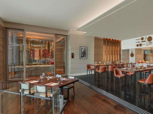 a restaurant with tables and chairs in a room at Sofitel Bangkok Sukhumvit in Bangkok