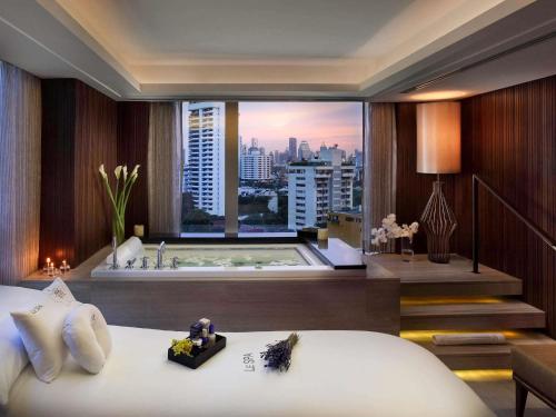 a hotel room with a large window with a bath tub at Sofitel Bangkok Sukhumvit in Bangkok