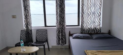 a room with a bed and a table and a window at Sea Breeze Cherai Homestay in Pallipuram