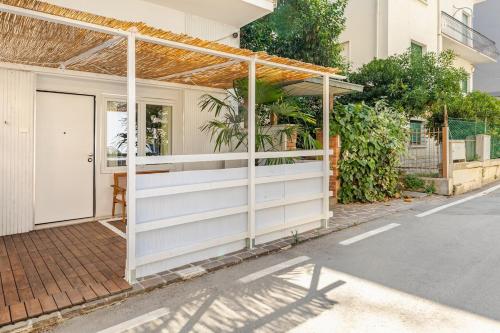 a white house with a pergola on a street at a 75 passi dal mare con parcheggio privato e giardino in Rimini