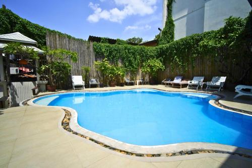 a swimming pool with chairs and a fence at Wild Orchid Villa Bangkok in Bangkok