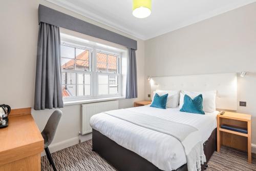 a hotel room with a large bed with blue pillows at Kingscliff, BW Signature Collection in Clacton-on-Sea