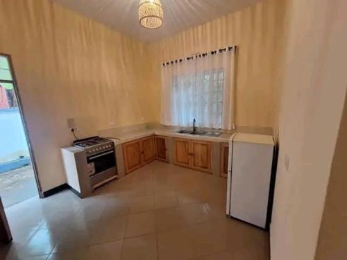 an empty kitchen with a stove and a refrigerator at Nungwi Vibes by Deo in Nungwi