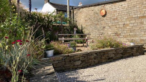 a garden with a stone bench and some plants at The Shearer's Hut in the Peak Park in Holme