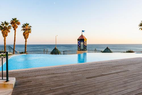 a swimming pool next to the ocean with a lighthouse at Britania Luxury in Parede