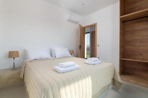 a bedroom with a white bed with two towels on it at Davlakos Villa Eve in Kremasti