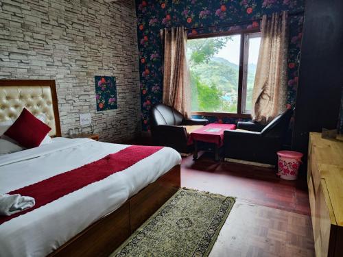 a bedroom with a bed and a chair and a window at Hotel Jannat in Solan
