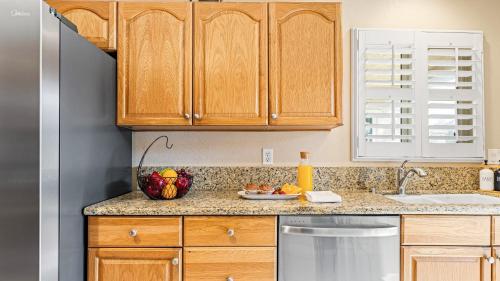 a kitchen with wooden cabinets and a bowl of fruit on the counter at Close to Beach w Patio Resort Amenities The Point at Corniche by AvantStay in Dana Point