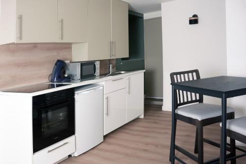 a kitchen with white cabinets and a table and a chair at Joli appartement neuf Proche gare Pèlerins et pro in Le Puy en Velay