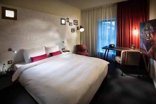 a hotel room with a large white bed and a desk at Penta Hotel Ipswich in Ipswich