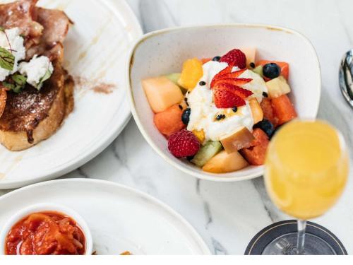 a table with plates of food and a bowl of fruit at Manly Pacific Sydney MGallery Collection in Sydney