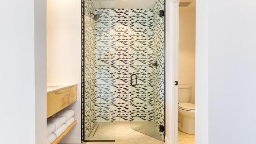 a shower with a glass door in a bathroom at Blackhaus D: 4 Bedroom Suite by AvantStay 4-Room Retreat in Palm Springs
