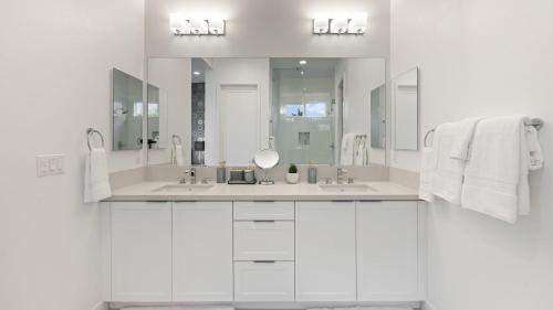 a white bathroom with two sinks and a mirror at Lumen at Tahquitz: New Build with Pool Fire Pit Designer Interiors in Palm Springs