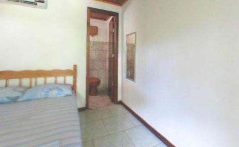 1 dormitorio con 1 cama y puerta que da a un pasillo en Pousada Brasil Tropical, en Ilha do Mel