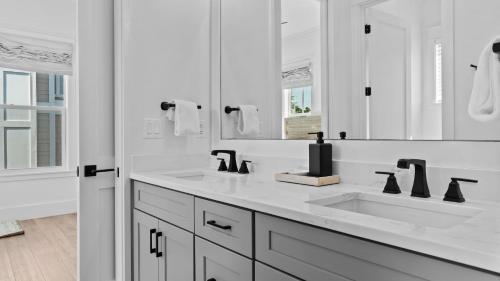 a white bathroom with two sinks and a mirror at 4BR Coastal Retreat w Pool Patio Games Lagniappe at Blue Mountain in Blue Gulf Beach