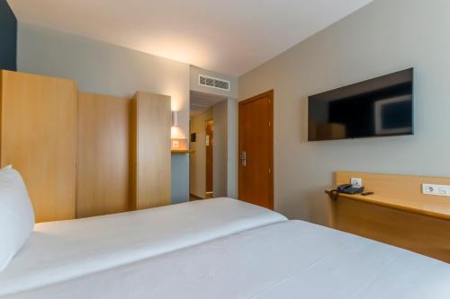 a bedroom with a white bed and a television at Travelodge Madrid Alcalá de Henares in Alcalá de Henares