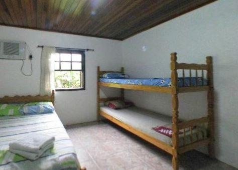 a bedroom with two bunk beds and a window at Pousada Brasil Tropical in Ilha do Mel