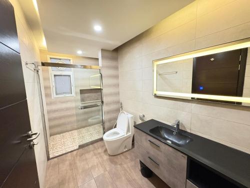 a bathroom with a toilet and a sink and a mirror at Elysium Premium Centaurus View in Islamabad