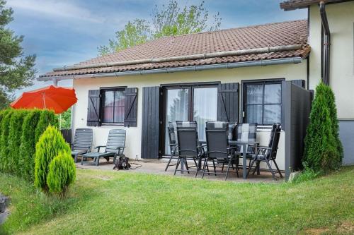 a house with a patio with chairs and an umbrella at Lechsee Lodge - Haus Bergliebe Nr 4 in Lechbruck