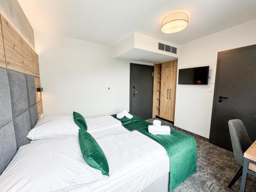 a hotel room with two beds with green pillows at Anmago Apartamenty & SPA in Krynica Zdrój