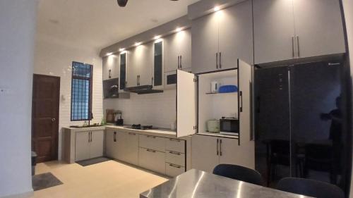クアラ・カンサーにあるHomestay Makyuのキッチン(白いキャビネット、黒の電化製品付)
